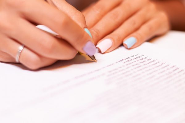 Close up of woman writing on clipboard during podcast. Influencer taking notes on clipboard while talking with followers during live on social media, creative online show On-air production broadcast